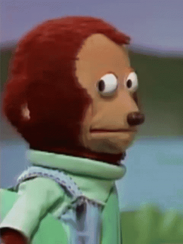 a-close-up-of-a-stuffed-monkey-wearing-a-green-shirt-and-overalls-making-a-funny-face.gif